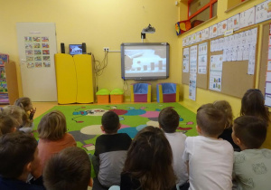 Grupa dzieci ogląda film edukacyjny na tablicy interaktywnej.